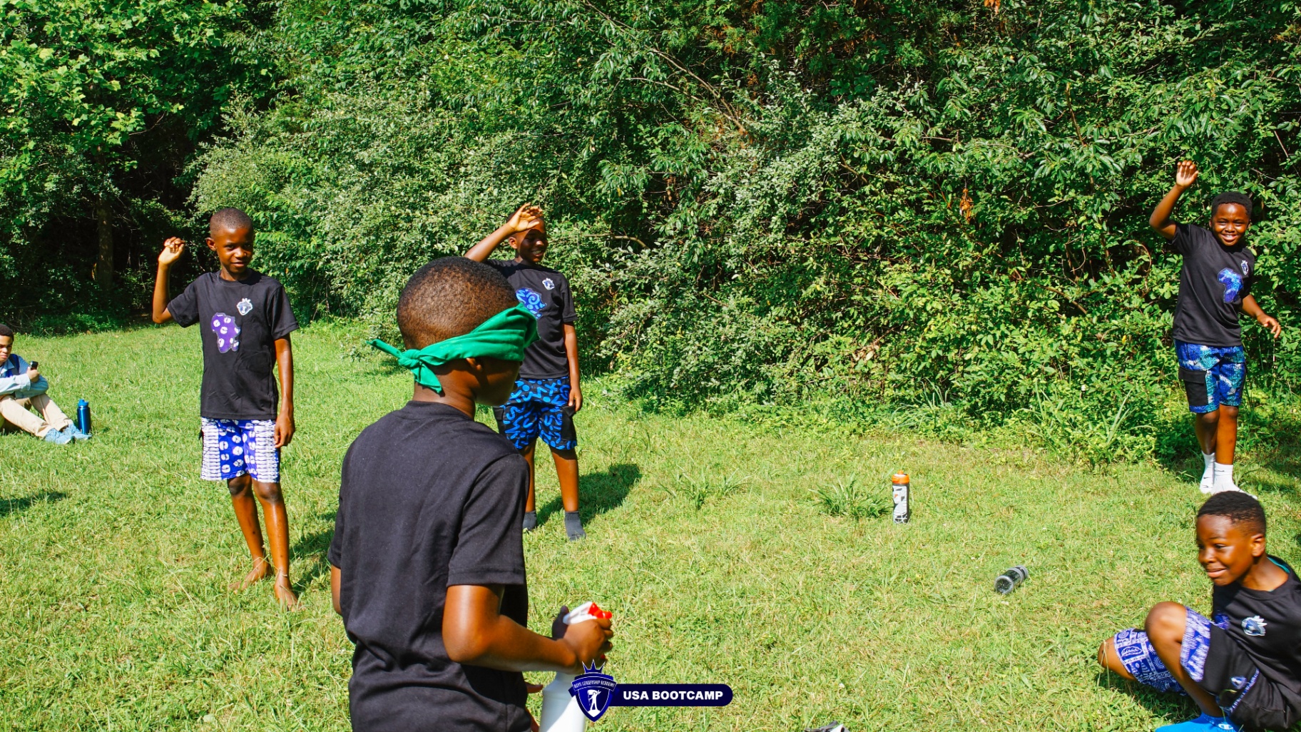 Boys playing a blindfolded team game on the grass.