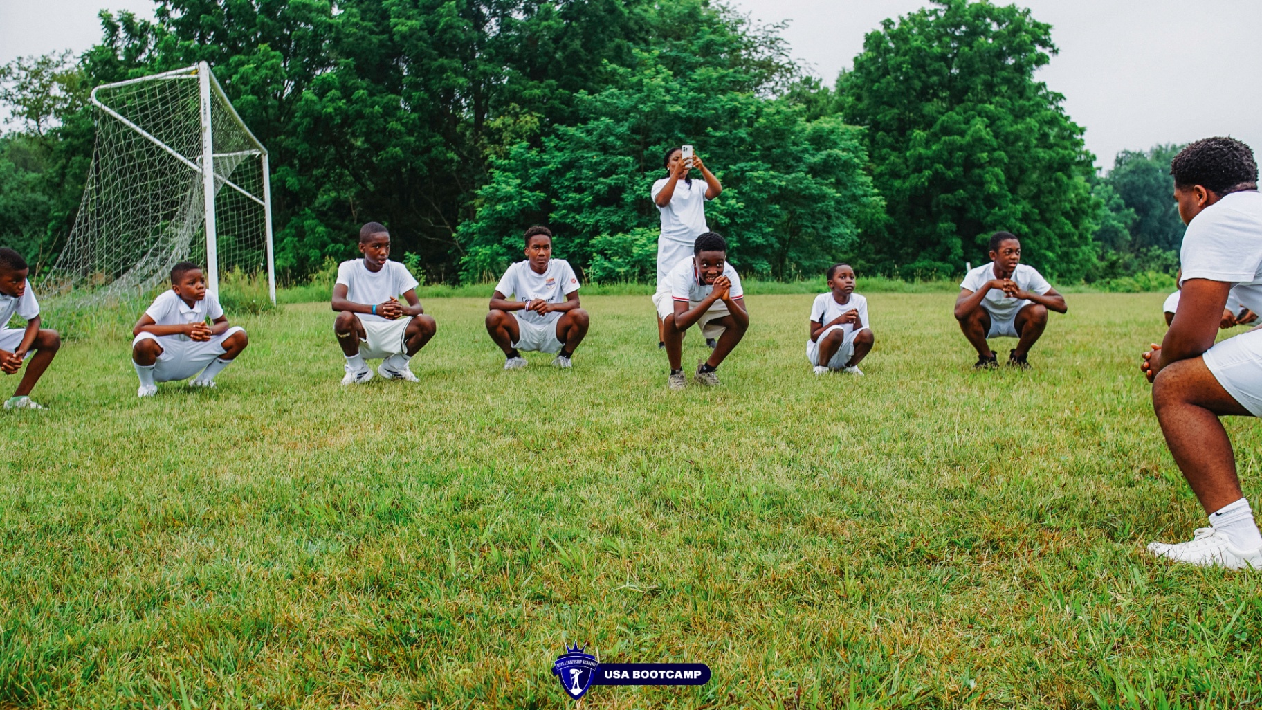 Boys squatting together on the soccer field during training.