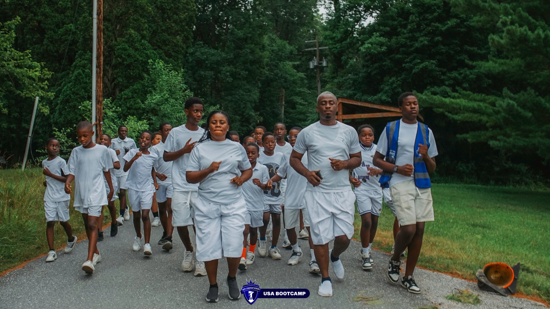 Group of boys and mentors running together on a wooded road.