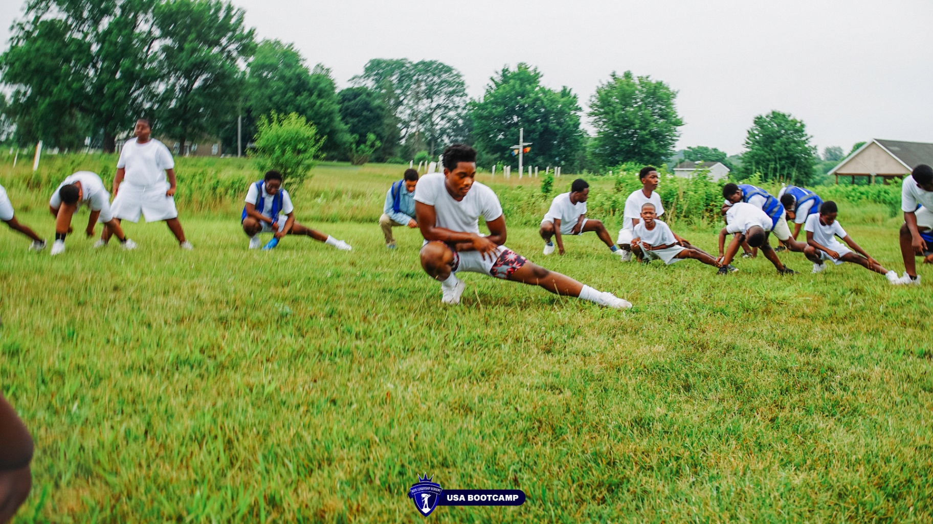 Boys stretching together in a field during morning drills.