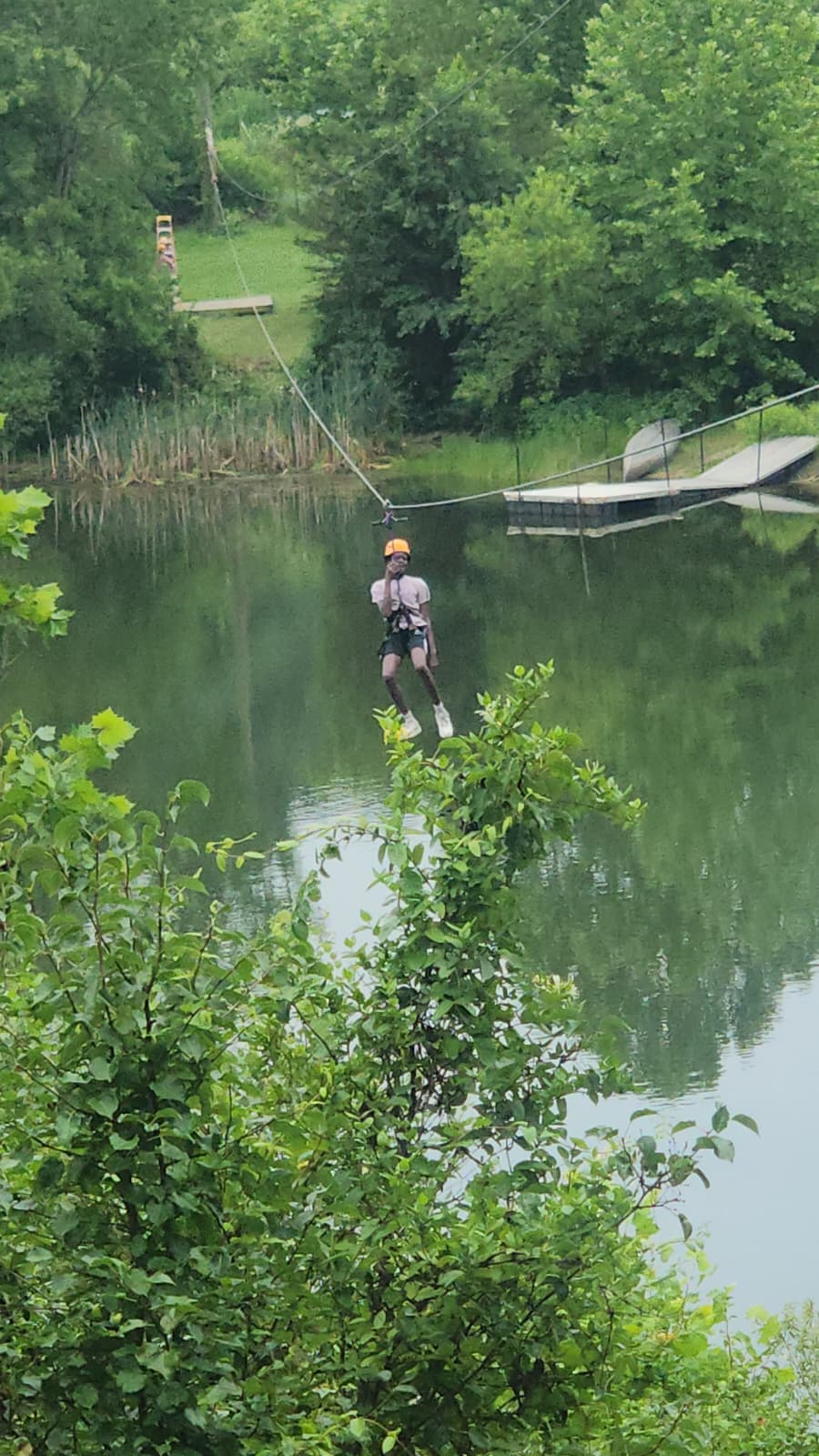 A camper riding the zip line across the lake.