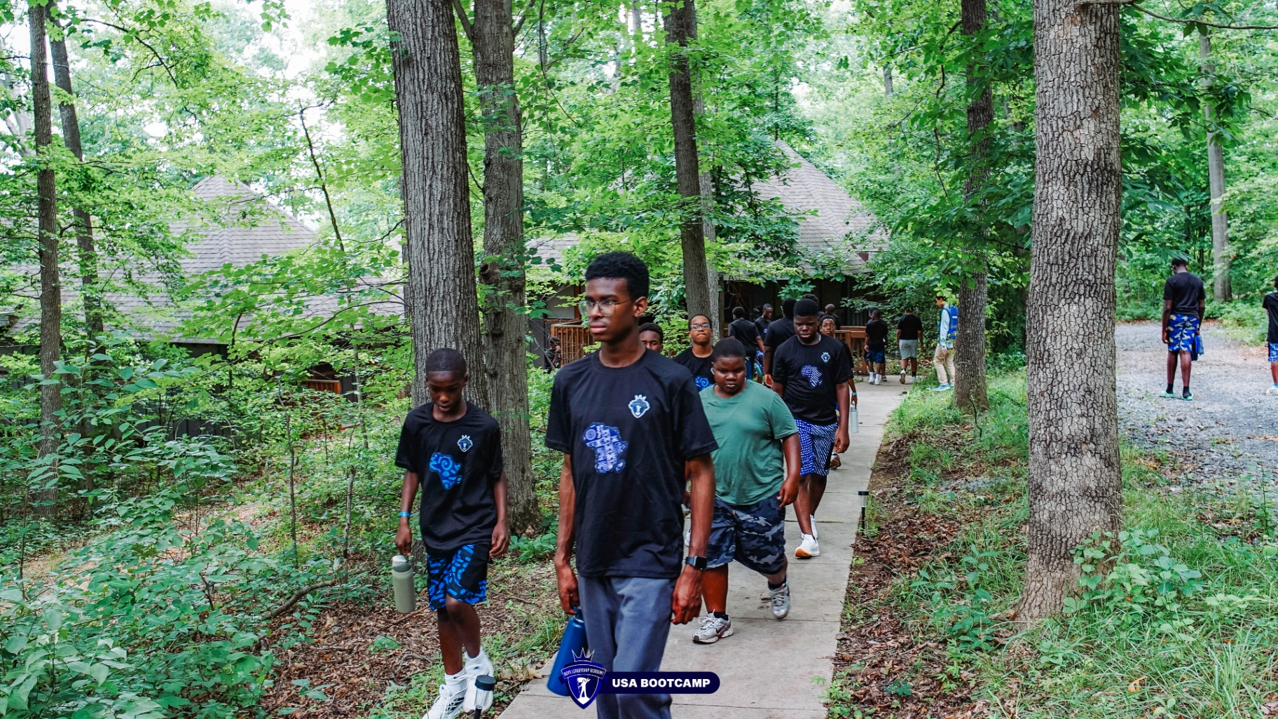 Campers walking a wooded path between cabins.